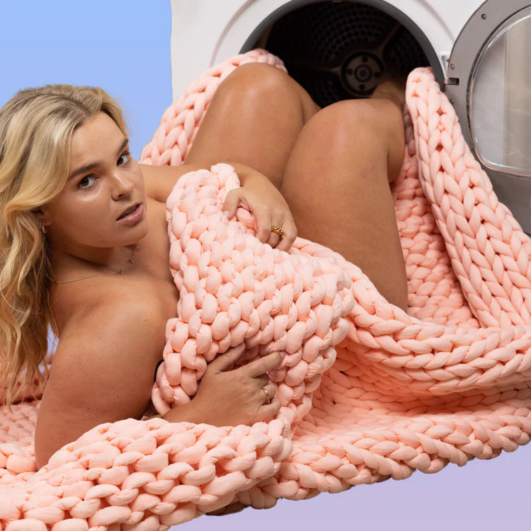 Model wearing a chunky knit throw which is being tossed in the washing machine
