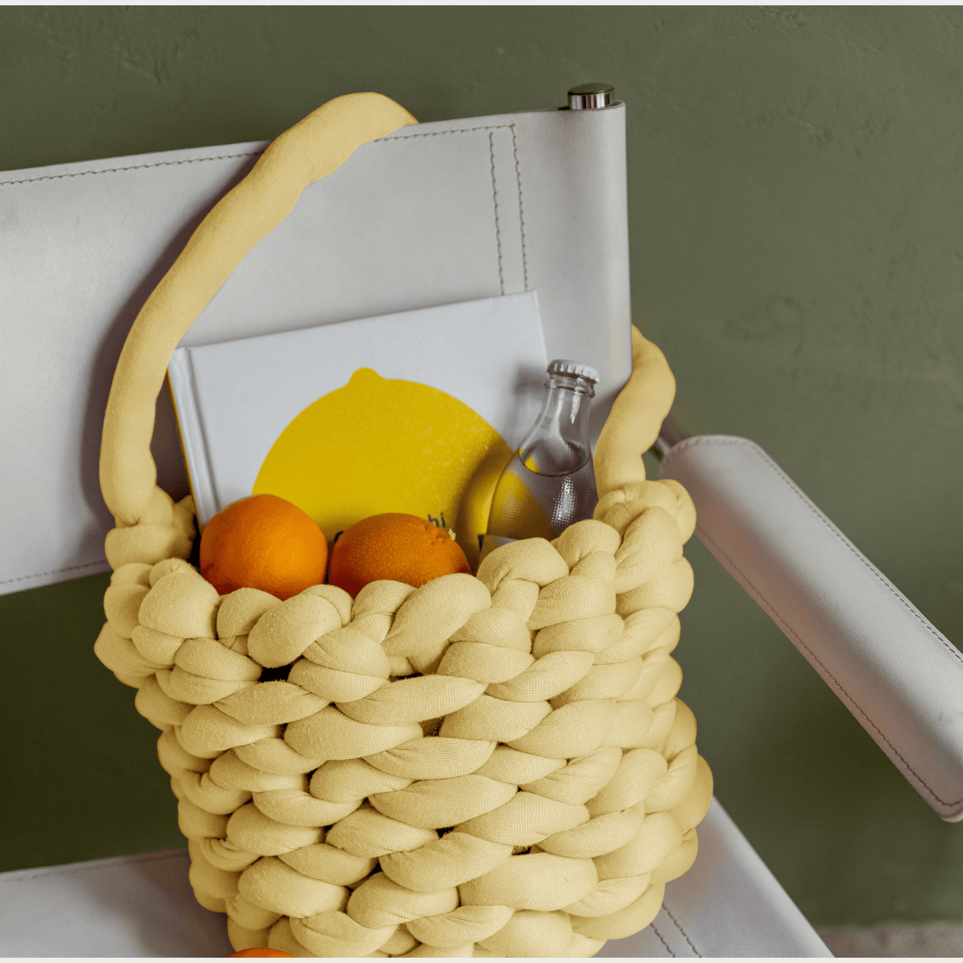 Chunky tote in yellow filled with some books, fruit and sparkling ater
